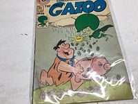 Front cover of The Great Gazoo comic book featuring Fred Flintstone holding a piggy bank with The Great Gazoo flying above raining coins.