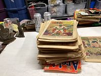 Stacked coverless comic book pages in various states of wear, some character pages visible such as a robot-themed comic.