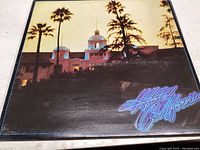 Front cover of the Eagles Hotel California vinyl record showing hotel exterior with palm trees and neon title.