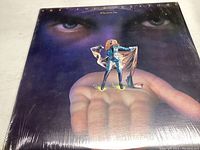 Front cover of The Four Seasons "Who Loves You" album showing artwork with a hand and miniature figure.