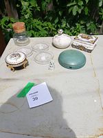 Full lot arranged on table including Swarovski bear, crystal coasters, small decorative jewelry boxes and glass jar with cork lid