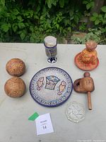 All assorted decorative items including a mosaic plate, wooden rattles, ceramic mug, pottery vase, percussion instrument, and glass ashtray
