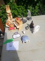 Photo of assorted rabbit figurines on table including wood, crystal, pewter, and ceramic pieces with a Budapest turtle.