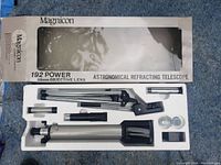 Opened box showing telescope components in white foam insert including main telescope tube, tripod, eyepieces and accessories.