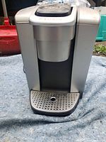 Front view of Keurig coffee maker showing silver and black body with drip tray.