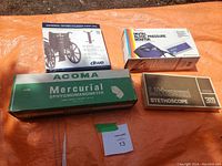 Photo of four boxed medical items: Littmann Stethoscope, Digital Blood Pressure Monitor, Acoma Mercurial Sphygmomanometer, Drive Oxygen Cylinder Carrier Bag.