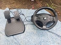 Photo of racing wheel and pedals together showing overall condition and wiring.