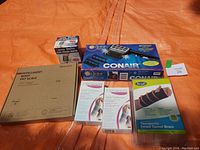 Photo showing the full lot including the scale box, Conair hair straightener box, two 3M Tensor wrist supports, therapeutic carpal tunnel brace and small blood pressure monitor box.