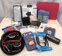 Photo showing lot items: Jabra headphones in case, Strikepack mod pack box, Handy Mini Fan box, ASUS USB-BT500 Bluetooth adapter, Jabra earbuds in open charging case, phone case with cartoon corgi, various cables and accessories.