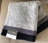 Folded grey and black Madison Park bath rug showing plush texture and color block design.