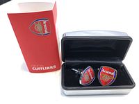 Photo of the Arsenal cufflinks displayed inside the black velvet presentation case with the red Official Arsenal cufflink box next to it.