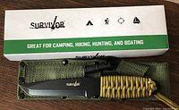 Photo of a boxed Survivor pocket tool set including a fixed blade knife, nylon sheath, and paracord accessory, shown for condition and contents.