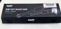 Box of OMT heavy duty tailgate shock showing product branding and 'without drilling' installation note.