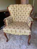 Front view showing the floral patterned fabric upholstery, wingback design, and wooden trim details on the armchair.