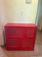 Front view of red solid wood bar cabinet with woven panel doors and brass hardware.