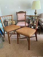 Photo of three chairs: two chairs with woven seat upholstery and a pink upholstered chair with carved wooden backrest.