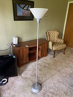 Full view of the floor lamp standing approximately 59 inches tall, featuring a white plastic conical shade and metallic silver pole and base.