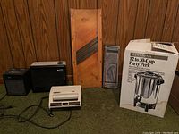 Photo of electric sandwich press, two small fans, wooden mandoline slicer, metal manual slicer, and boxed West Bend Party Perk coffee dispenser.