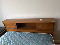 Front view of walnut headboard with central open compartment and sliding door partially open, mattress in front