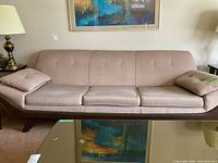 Full front view showing three-seat sofa with button-tufted back and two loose armrest cushions.