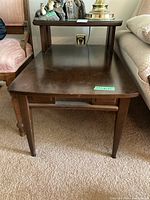 Front and top view of rectangular two-tier wood side table with visible scratches on surface and removable mirrored glass on upper shelf.