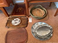 All trays together on the floor showing the variety of materials: metal, wood, and wicker.