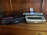 Photo showing full lot with Sansui VCR and Smith-Corona electric typewriter side by side on a wooden shelf.