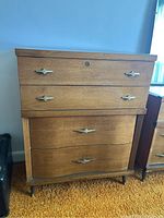 Front view of Mid-Century Modern tall dresser showing four drawers with metal handles and keyhole on top drawer.