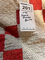 Close-up of quilt fabric showing red and cream nine patch pattern with black shirting print fabric and turkey red solid.