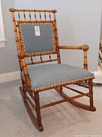 Front and side views of an antique rocking chair with upholstered blue seat and backrest, featuring bamboo-style turned spindle wood frame and armrests.