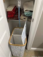 Closet shelf with folded assorted towels and two rectangular fabric laundry hampers below