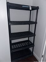 Full view of the black plastic shelf showing all five tiers with lattice design