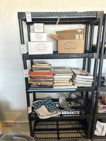 Front view of the shelf with some items placed on different shelves like boxes, books, a fan, and miscellaneous items.