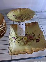 Photo showing a square, scalloped cake plate with floral pattern and gilt edge along with one serving dish
