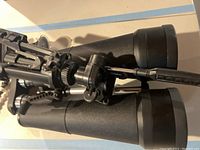 Close-up of black Celestron Skymaster binoculars with textured grip and part of attached adjustable mount.