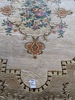 Close-up showing the floral design and cream background with a note identifying the rug.