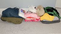 Stack of various ladies clothes including tops, sweaters, jeans and slippers showing colors and condition