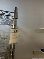 Close-up of metal shelf pole with attached hang tag labeled 'metal shelf'.