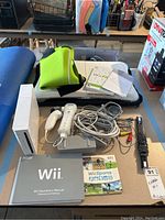 Nintendo Wii console with accessories including controllers, cables, manuals, game discs, and balance board.