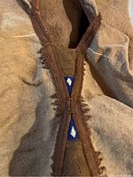 Close-up of the fabric and seam showing the brown cape's textured material and decorative edging with blue and white triangular inserts.