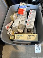 Bin containing multiple boxes of UIC giant gem clips, color coding labels, Highland yellow legal pads, and other stationery supplies