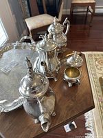 Photo showing six-piece silver Rogers tea service set with coffee pot, teapot, sugar bowl, creamer, and serving tray on wood surface.