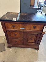 Front view of the vintage solid wood table with natural stone top showing drawers and door.
