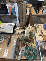 Table display showing wooden wind chime parts, metal chimes, starfish and seashell decorations, and stained glass pieces