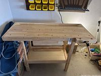 Front view of wooden workbench showing top surface with holes and pullout drawer below.