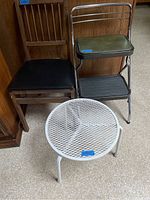 Three chairs and one round metal mesh table grouped together on a floor.