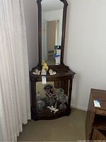 Full view of the mirrored wooden corner display stand with glass-fronted base cabinet and decorative carved edges.