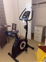Front and side view of Pro-Form exercise bike showing seat, handlebars, pedals and digital display screen.