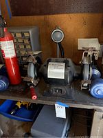 Photo of bench grinder with fire extinguisher and weight plates on bench.