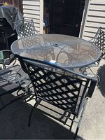 Photo showing round iron mesh patio table with lattice back chair.
